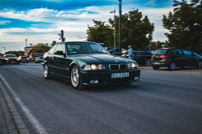 a black car driving down a street next to parked cars