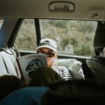 Person in car reading a book during a trip.