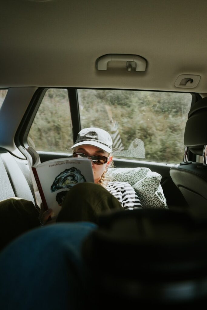 Person in car reading a book during a trip.